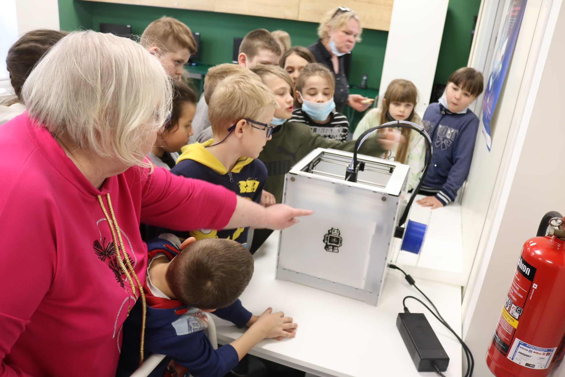 Dzieci podczas lekcji bibliotecznej w pracowni drukarki3D w trakcie pracy drukarki 3D