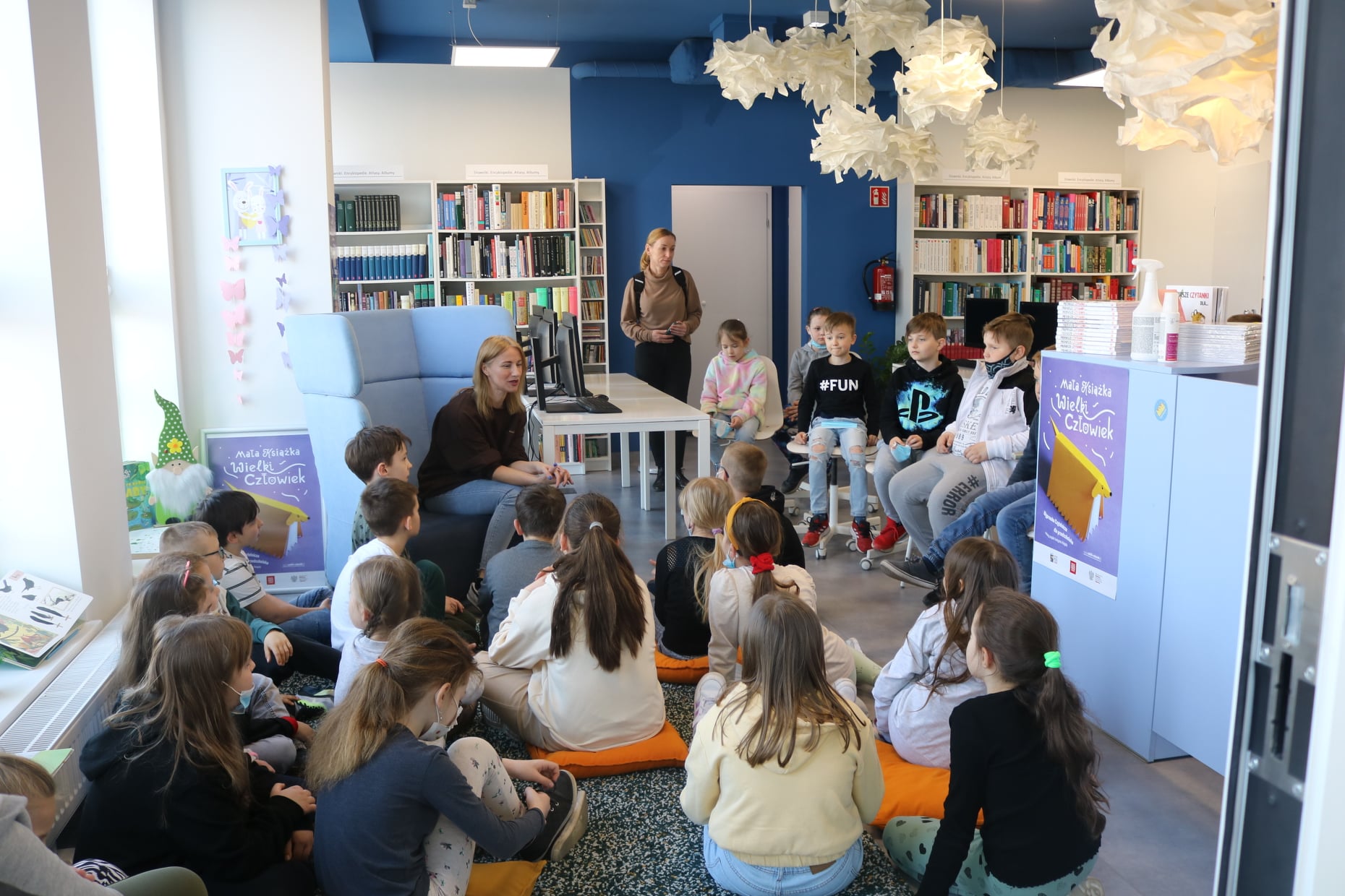 Dzieci siedzące na podłodze i słuchające informacji o bibliotece